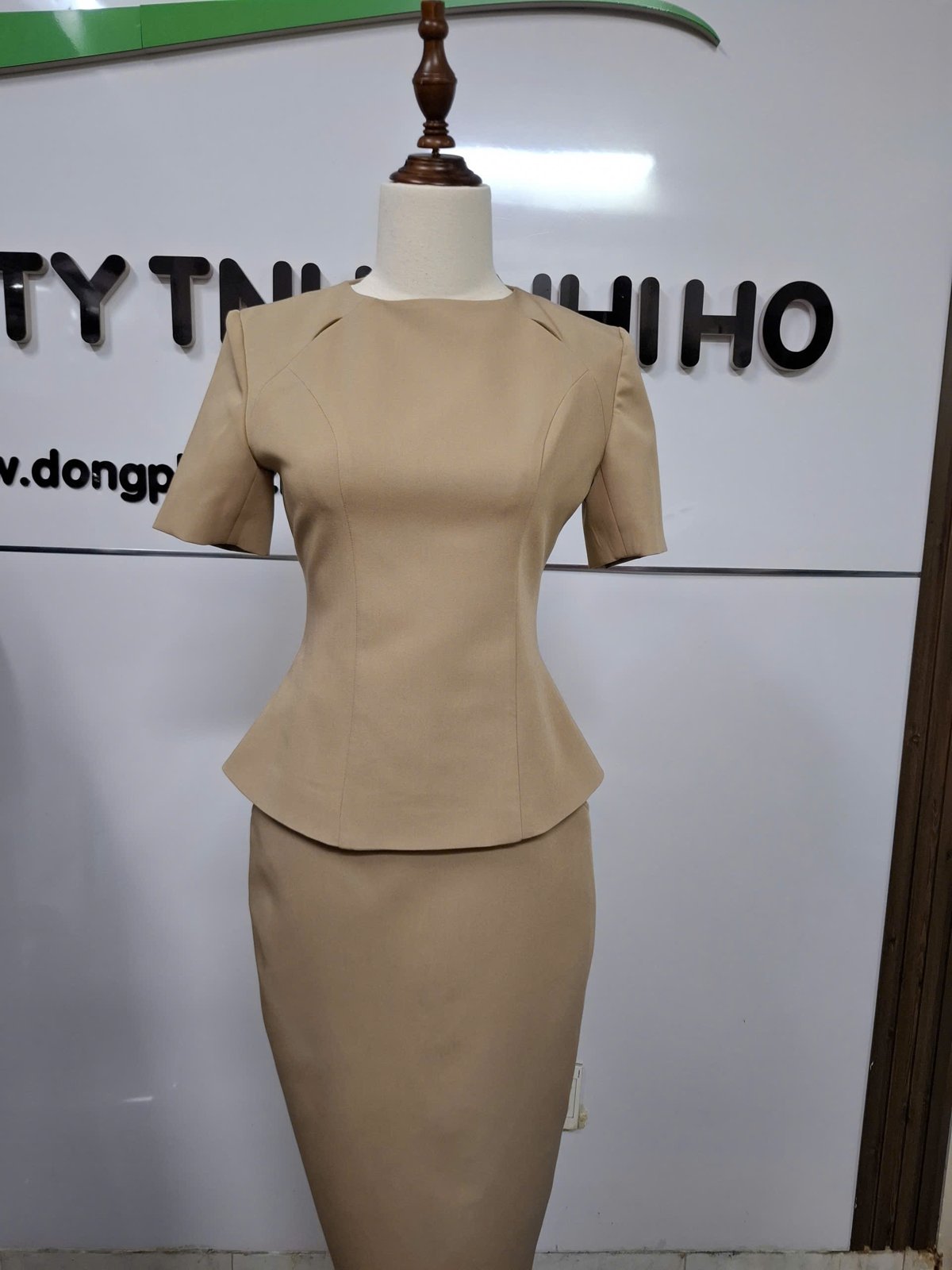 Đầm đồng phục nữ màu be, eo peplum, tay ngắn, dài qua gối