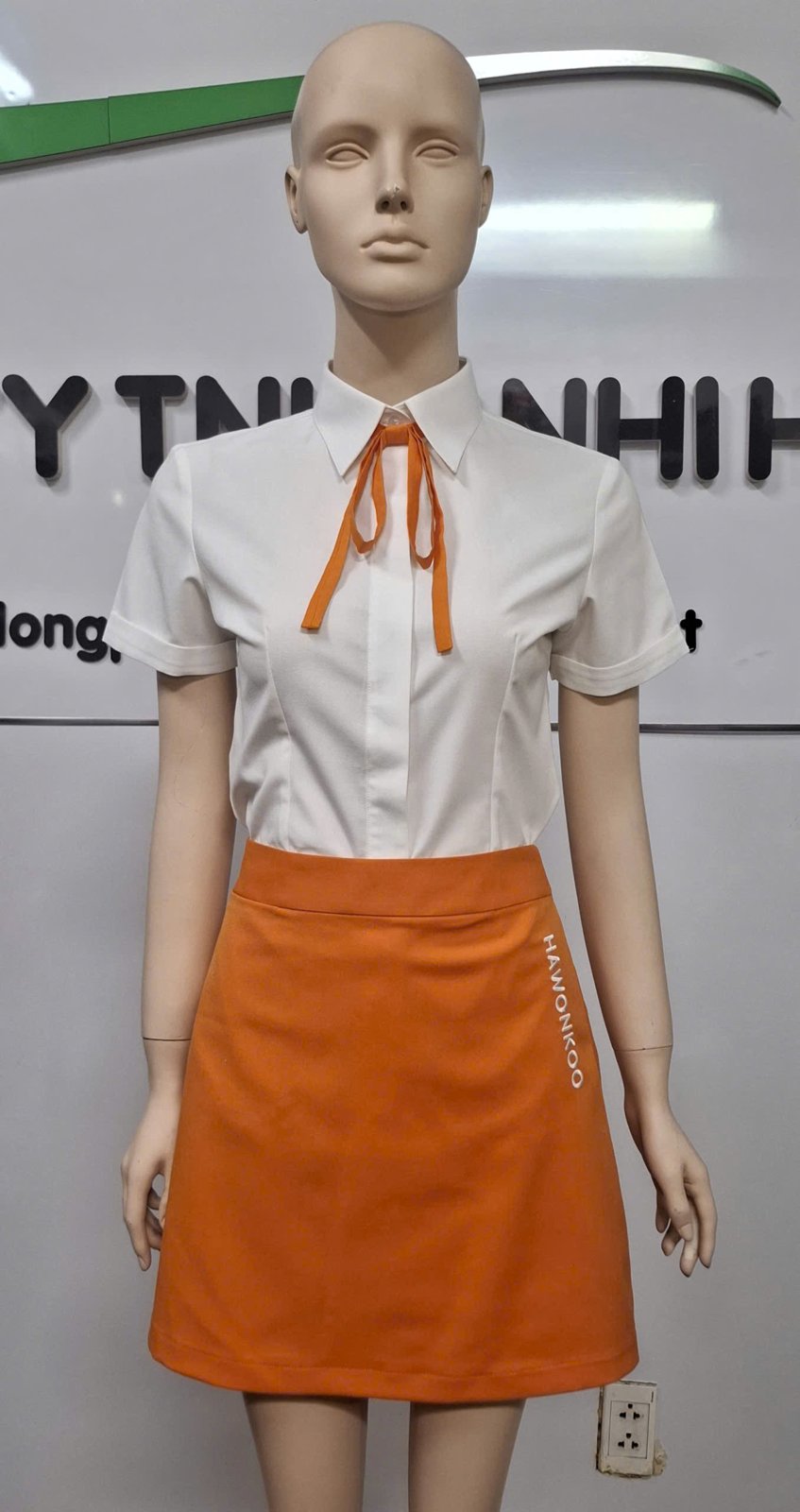 Sơ mi nữ trắng tay ngắn thắt nơ cam, chân váy chữ A màu cam